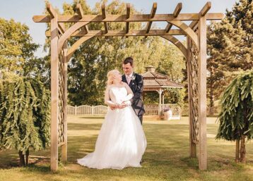 Bride and groom posing under a wooden archway