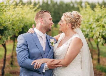 Newlyweds posing together amongst a vineyard