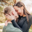 A young couple embracing and laughing together in a country park