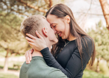 A young couple embracing and laughing together in a country park