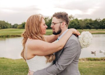 Bride and groom embracing in front of a lake