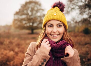 Girl in a bobble hat and scarf in autumnal parkland