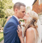 A wedding couple sharing a romantic kiss outside a rustic countryside pub