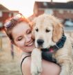 Girl smiling holding a Golden Retriever puppy in her arms