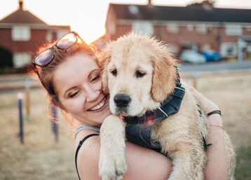 Girl smiling holding a Golden Retriever puppy in her arms