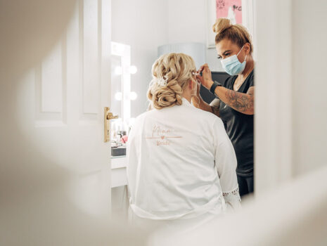 A bride having her hair and makeup done on the morning of her wedding