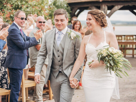 A wedding couple smiling as they walk back down the aisle after their wedding ceremony