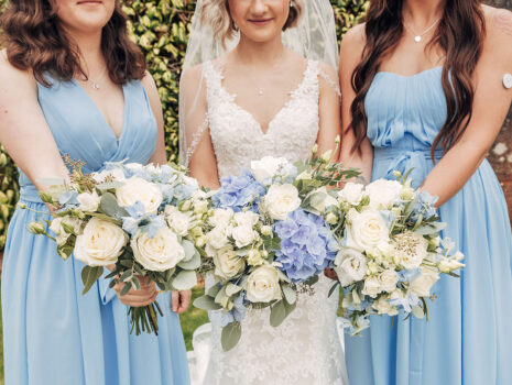 A bride and two bridesmaids holding out their bouquets