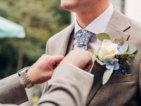 A groomsman adjusting a groom's tie during the morning before the wedding ceremony