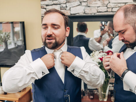 A groom and a groomsman getting ready on the morning of a wedding