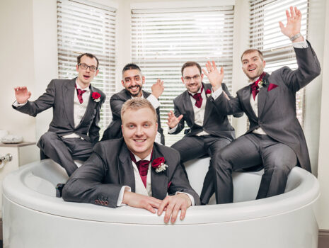 A groom and his groomsmen posing for a fun photo in a jacuzzi bathtub