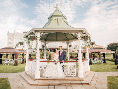 A wedding couple posing in a gazebo in the grounds of the Hythe Imperial Hotel