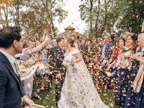 Wedding guests showering confetti over a bride and groom outdoors