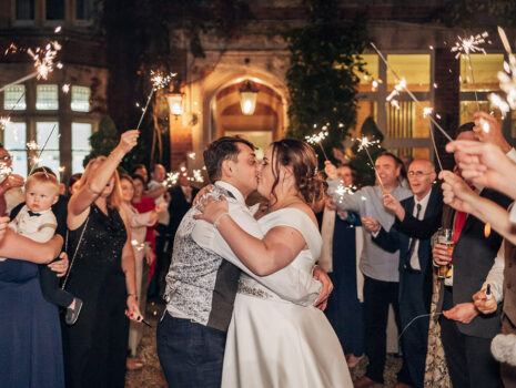 A wedding couple kissing during a sparkler exit outside their venue in Essex