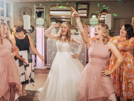 A bride, bridesmaids and guests dancing away during a wedding reception