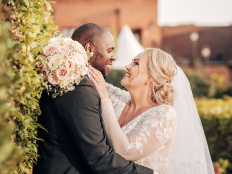 A wedding couple kissing and embracing at golden hour in the grounds of their venue