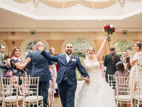 A wedding couple smiling and walking back down the aisle after their wedding ceremony