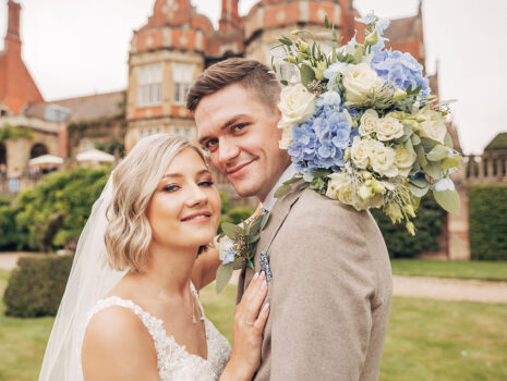 A wedding couple posing together in the grounds of Tylney Hall Hotel near Hook