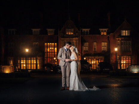A wedding couple kissing at night in front of Tylney Hall Hotel near Hook