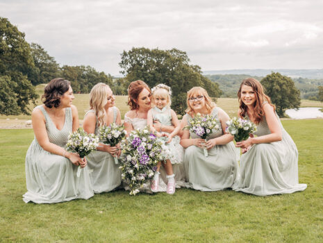 A bride, four bridesmaids and a flower girl posing together for a group photo